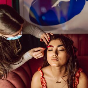 A makeup artist applies makeup to a woman indoors, showcasing beauty and skill.