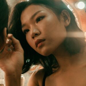 Close-up of a focused makeup artist applying cosmetics in a studio setting with warm lighting.