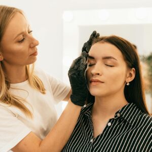 Makeup artist applying foundation in a well-lit studio setting, focusing on beauty and preparation.